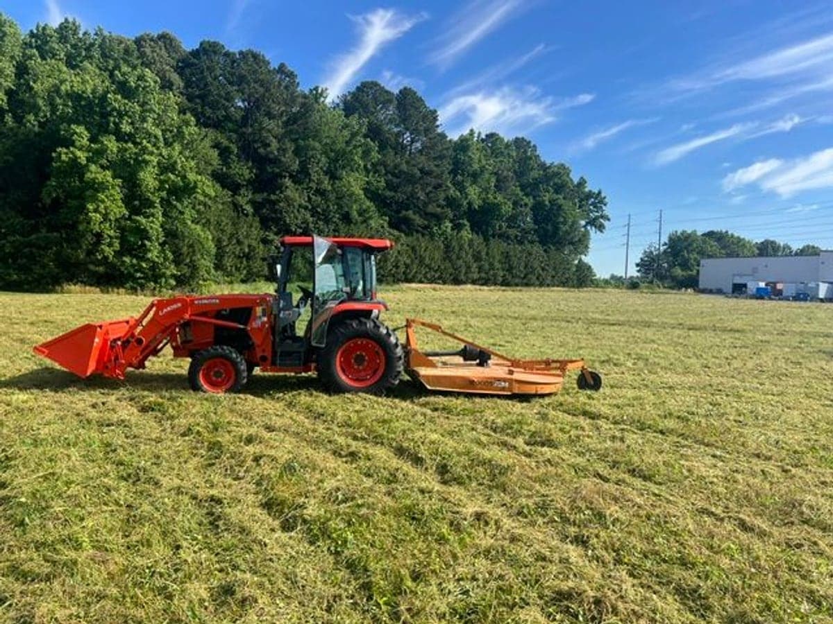 Compact tractor with a rotary brush cutter clearing an overgrown Eastern Shore field